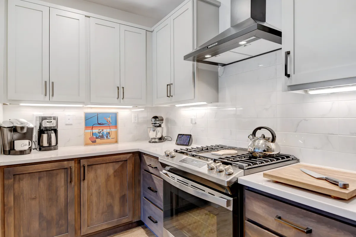 This image features a bright, welcoming kitchen with stainless steel appliances, white cabinetry, and a clean countertop. The space supports meal preparation and casual gatherings, providing a sense of home-like comfort and luxury.